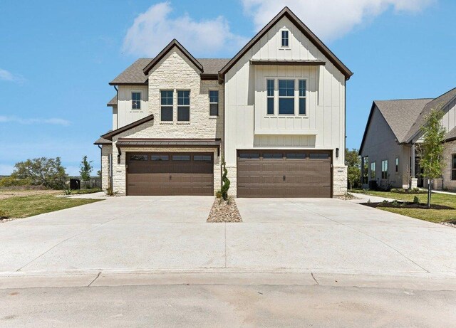 232 Flora Springs Cv, Liberty Hill, TX 78642 - view of front facade with driveway, board and batten siding, a garage, and stone siding