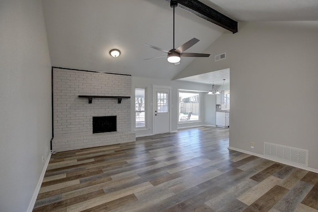 unfurnished living room featuring wood-type flooring, ceiling fan with notable chandelier, a fireplace, and beamed ceiling