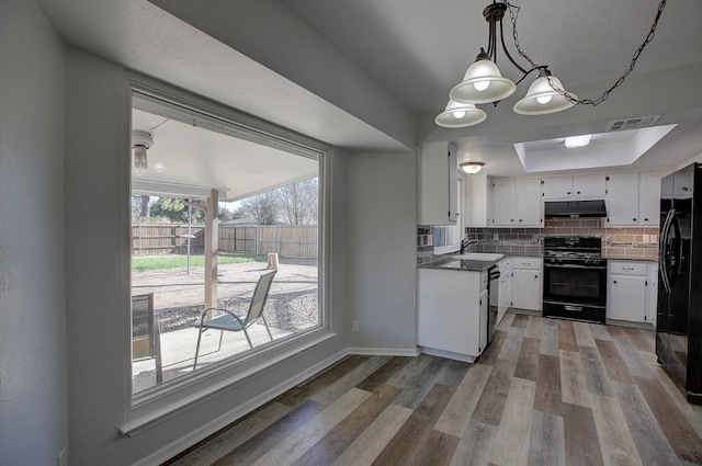 kitchen with white cabinetry, backsplash, black appliances, decorative light fixtures, and light wood-type flooring