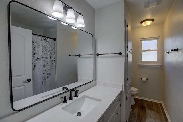 bathroom featuring vanity, toilet, hardwood / wood-style floors, and a textured ceiling