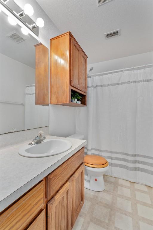 bathroom featuring vanity, walk in shower, and toilet