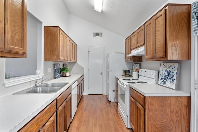 kitchen featuring lofted ceiling, sink, white appliances, and light hardwood / wood-style floors