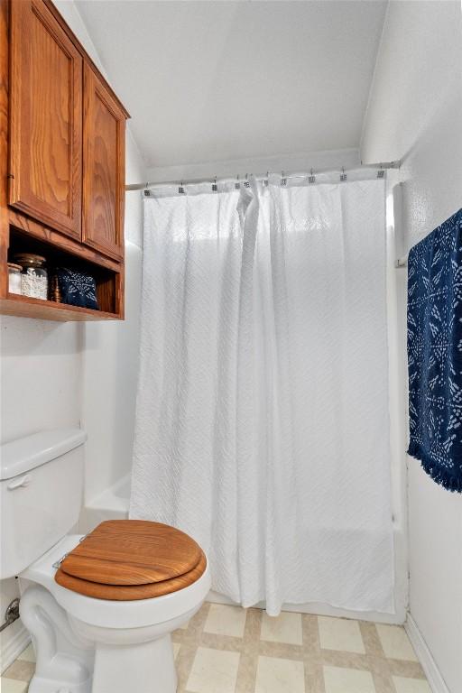 bathroom with curtained shower and toilet