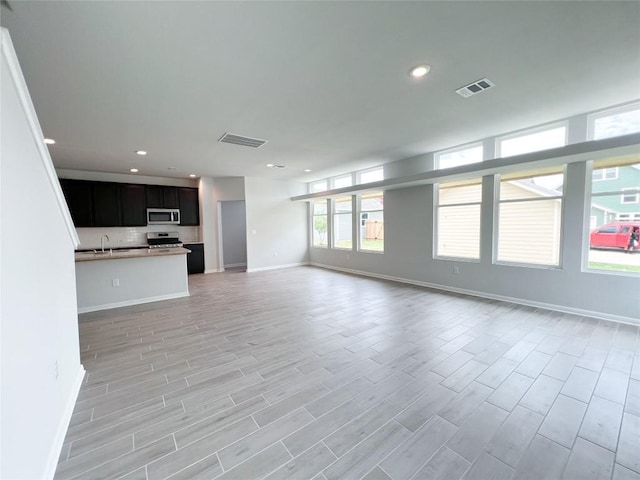 unfurnished living room featuring sink and light hardwood / wood-style flooring