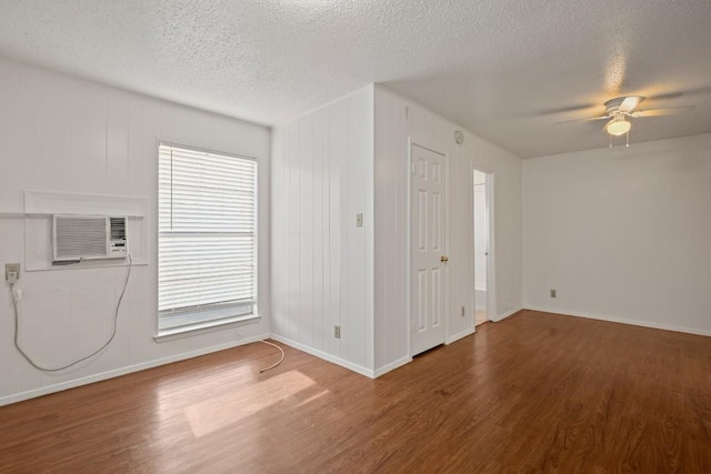 spare room with ceiling fan, hardwood / wood-style floors, a wall unit AC, and a textured ceiling