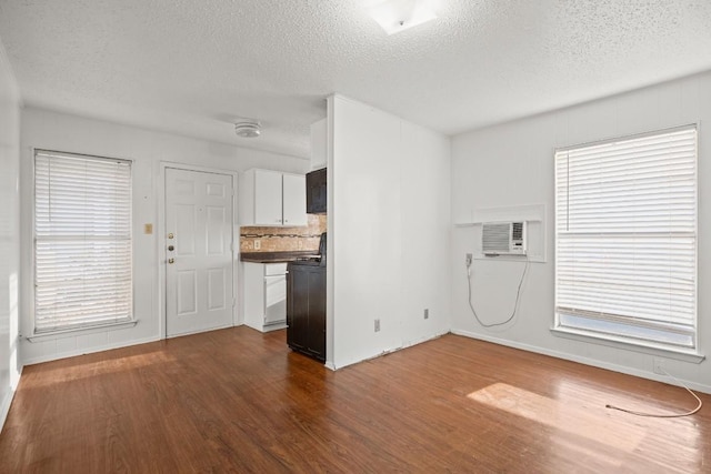 unfurnished living room with dark hardwood / wood-style floors, a wall mounted AC, and a textured ceiling