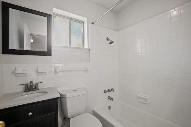 full bathroom featuring tiled shower / bath combo, vanity, tile walls, and toilet