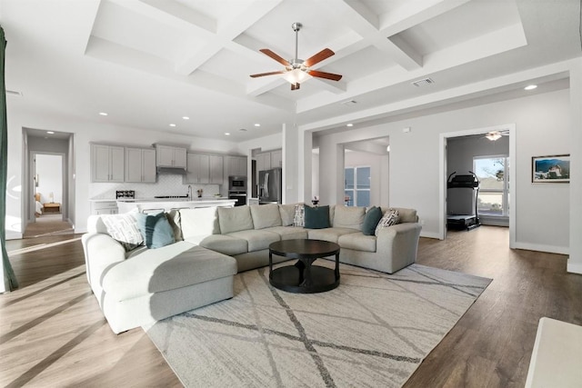 living area featuring beam ceiling, baseboards, coffered ceiling, and light wood finished floors