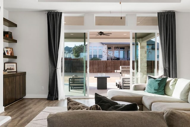 living room with light wood finished floors, plenty of natural light, a ceiling fan, and baseboards