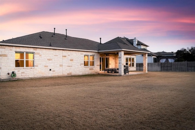 rear view of house with roof with shingles, a chimney, fence, and a patio