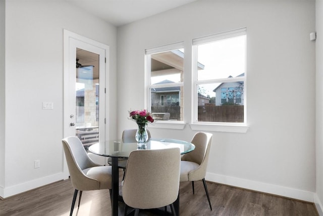 dining space featuring dark wood-type flooring and baseboards