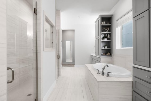 bathroom with a stall shower, a garden tub, and baseboards