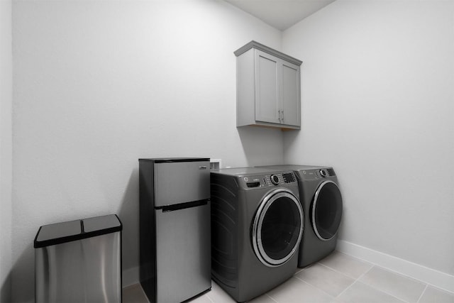 clothes washing area featuring cabinet space, washer and clothes dryer, baseboards, and light tile patterned flooring