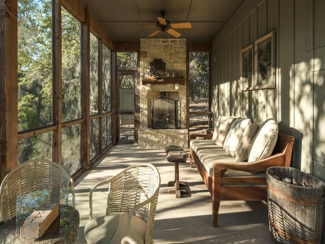 sunroom / solarium with ceiling fan and an outdoor stone fireplace