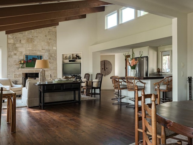 dining area featuring beamed ceiling, dark hardwood / wood-style floors, high vaulted ceiling, and a stone fireplace