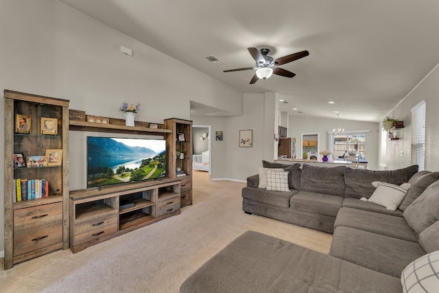 carpeted living room with ceiling fan with notable chandelier and vaulted ceiling