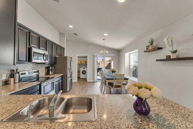 kitchen with decorative light fixtures, tasteful backsplash, lofted ceiling, sink, and stainless steel appliances