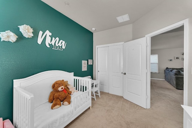 carpeted bedroom with a crib and a closet