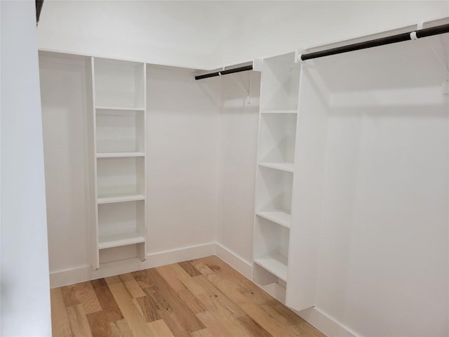 walk in closet with light hardwood / wood-style floors