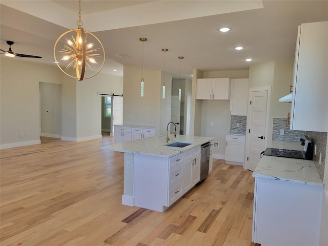 kitchen with white cabinetry, a barn door, sink, and a center island with sink