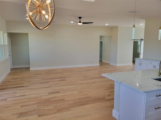 interior space with sink, ceiling fan with notable chandelier, light hardwood / wood-style flooring, and a barn door