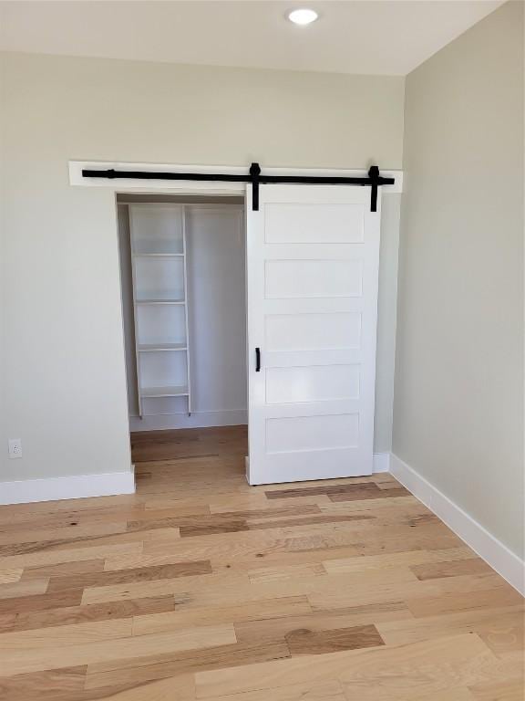 spare room with a barn door and light hardwood / wood-style flooring