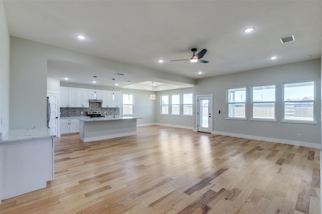 unfurnished living room with a ceiling fan, baseboards, recessed lighting, and light wood-type flooring