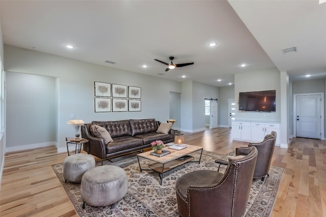 living area with baseboards, visible vents, a barn door, and light wood-type flooring