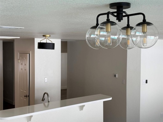 kitchen with a kitchen bar, kitchen peninsula, sink, and a textured ceiling