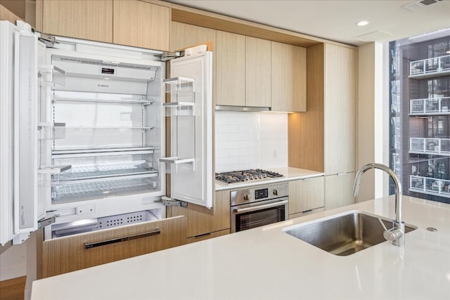 kitchen featuring stainless steel appliances, tasteful backsplash, sink, and light brown cabinetry