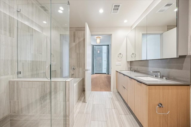 bathroom featuring tasteful backsplash, vanity, and a shower with door