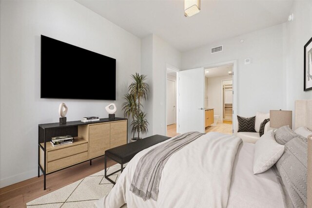 44 E Ave Unit 1407, Austin, TX 78701 - bedroom featuring light wood-style flooring, baseboards, and connected bathroom