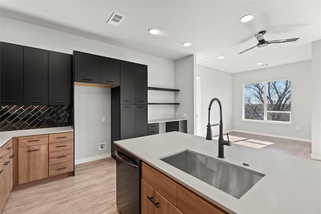 kitchen featuring black dishwasher, sink, backsplash, and light wood-type flooring