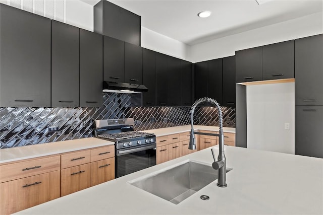 kitchen with gas range, sink, light brown cabinetry, and decorative backsplash