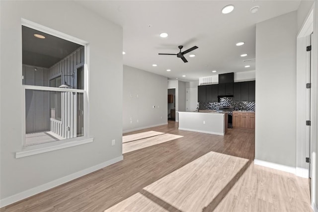 kitchen with tasteful backsplash, a center island, stainless steel stove, ceiling fan, and hardwood / wood-style floors