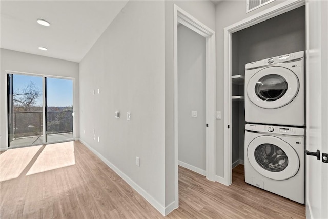 washroom featuring light hardwood / wood-style flooring and stacked washing maching and dryer