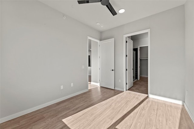 unfurnished bedroom with hardwood / wood-style flooring, ceiling fan, and a spacious closet