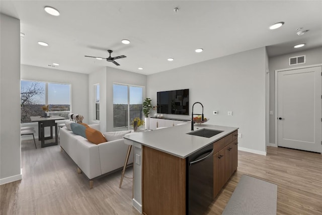 kitchen featuring sink, an island with sink, dishwasher, and light wood-type flooring