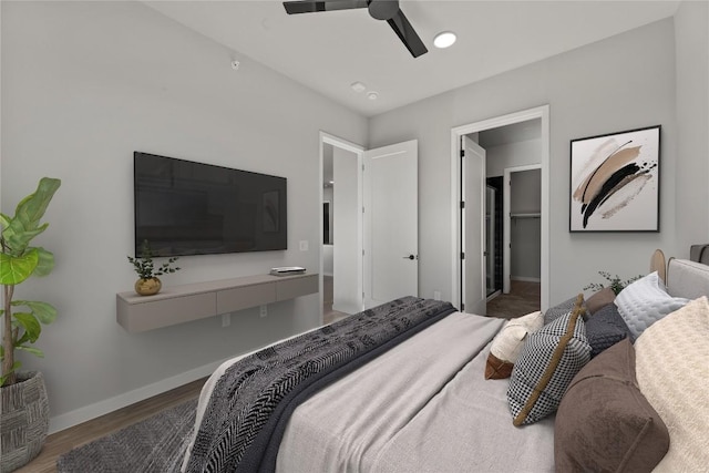 bedroom with a walk in closet, hardwood / wood-style floors, and ceiling fan