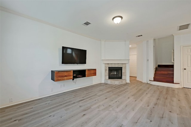 unfurnished living room featuring ornamental molding, a fireplace, and light hardwood / wood-style flooring