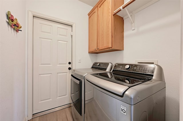 clothes washing area with cabinets, wood-type flooring, and separate washer and dryer