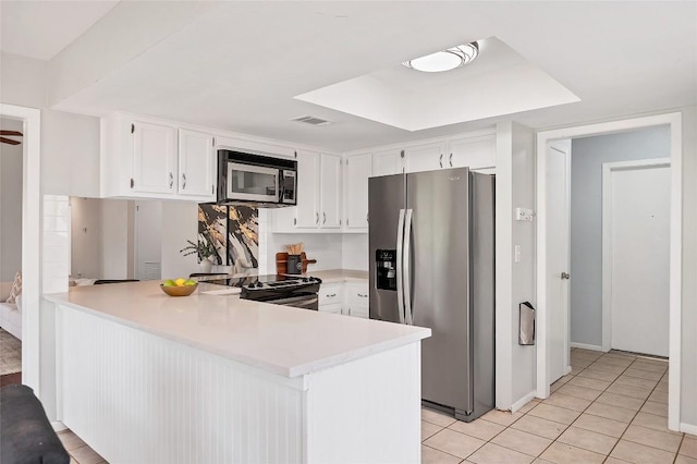 kitchen with light tile patterned floors, a peninsula, white cabinets, light countertops, and appliances with stainless steel finishes