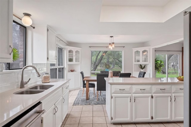 kitchen with light countertops, a sink, dishwasher, and white cabinetry