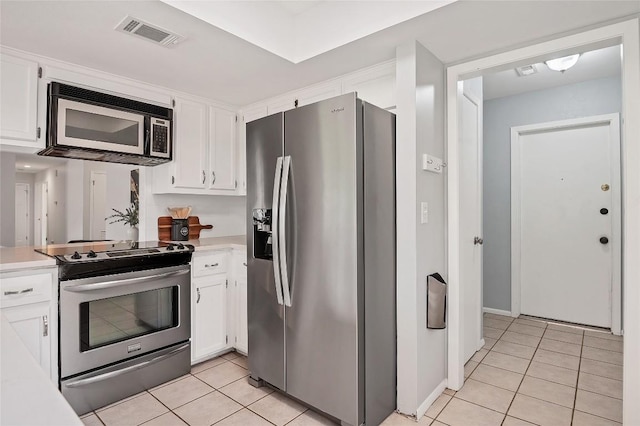 kitchen featuring light tile patterned floors, stainless steel appliances, visible vents, and white cabinets