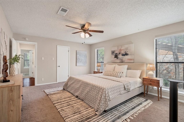 carpeted bedroom with ceiling fan, a textured ceiling, visible vents, and baseboards