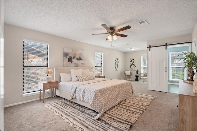 bedroom with carpet, a barn door, multiple windows, and visible vents