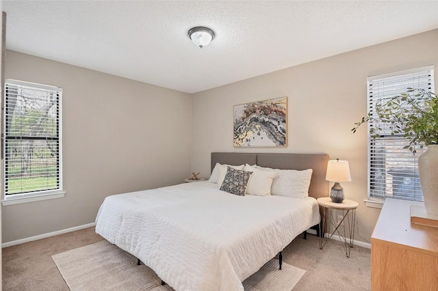 bedroom featuring light colored carpet, a textured ceiling, and baseboards