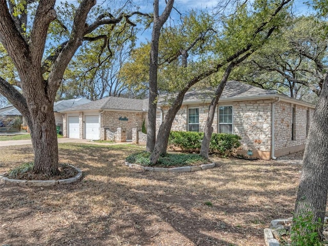 ranch-style house featuring a garage and stone siding