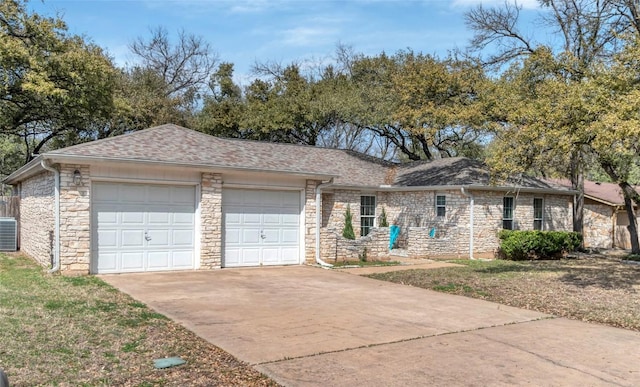 ranch-style house featuring roof with shingles, central air condition unit, concrete driveway, a garage, and stone siding