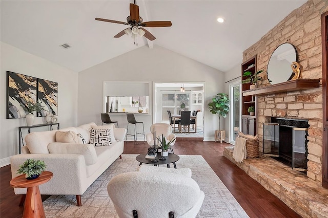 living area with a stone fireplace, dark wood-type flooring, visible vents, and baseboards